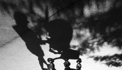 Blurry shadow of a woman with postpartum depression pushing a baby trolley on the cracked asphalt suburban park road in black and white