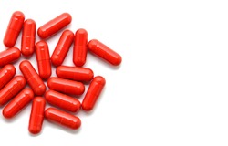 Heap of red pills isolated on white background. Macro. Close up view. Tablets scattered on a table. Pharmacy. Treatment. Copy space for your text