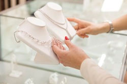 Unrecognizable women choosing diamond necklaces at jewelry store