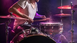 The drummer plays the drums. Beautiful blue and red background, with rays of light. Beautiful special effects smoke and lighting. The process of playing a musical instrument. The concept of music.