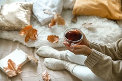 Cozy autumn at home, a woman with tea and a book resting. A cozy way of life . Body parts in the composition.
