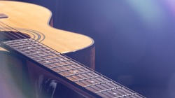 Acoustic guitar with a beautiful wood on a black background in the light of a spotlight.