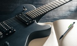 Close-up, electric guitar and notepad, concept of musical creativity.
