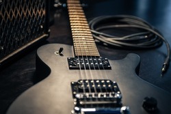 Close-up, black electric guitar on a dark background, the concept of musical creativity, modern musical instruments.