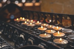 Many small candles in a Catholic church in a dark interior.