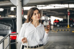 Attractive business young woman in a car park with a cup of coffee.