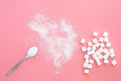 Scattered sugar and sugar cubes on a pink background, flat lay.