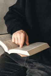 Open book Bible in male hands, close-up.