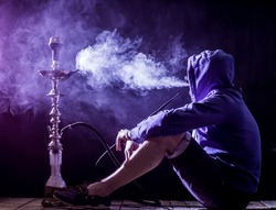 a man smokes a hookah on a black background, holiday concept, beautiful lighting
