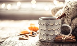 Details of still life in the home interior living room. Beautiful Cup of tea with tangerines and sweaters on wooden background . Cosy autumn-winter concept