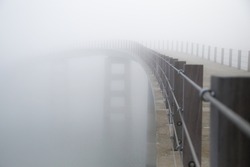 Curved bridge vanishing in  heavy fog.