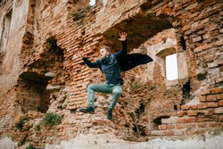 Adult crazy angry unusual excited male portrait. Businessman in flight motion. Young boy with funny comic expressive odd face emotions jumping from brick wall. Flying person. Sport activity outdoor