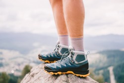 Mood photo of male legs wearing sportive hiking shoes with strong protective sole. Mens legs in trekking footwear for mountain travel standing on stone outdoor at nature on abstract background