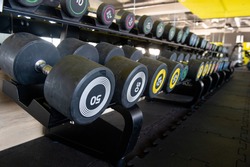 Row of dumbbells in gym. Colorful dumbbell set in sport fitness club center.