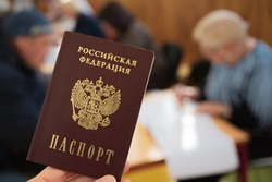 Closeup of national passport of the Russian Federation in the hand on the background of blurry people at the elections