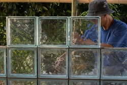 Construction worker as a mason man building glass brick block wall background. Selective focus and copy space.