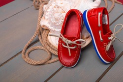 Red boat shoes on big shell and rope on wooden background. Close up. 