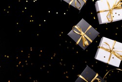 Black and white gift boxes with gold ribbon on shine background. Flat lay. Copy space