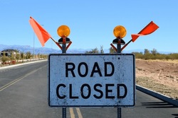 road closure construction barricade sign with bright orange caution flags