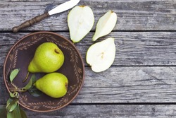 pears in a plate and slices of pears top view. wooden background with pears. ripe organic pears close-up.