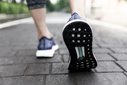 A close up shot of athlete shoes. The athlete is standing on a tiled floor prepare to start her exercise.