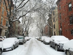 View down a street with parked cars in Park Slope, Brooklyn in the winter of 2015 with snow falling