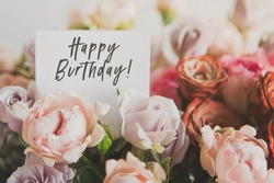 beautiful bright bouquet of colorful roses with white card with the inscription happy birthday, concept of congratulations on the holiday