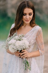 Portrait of bride with bouquet. Young beautiful bride holds wedding bouquet in her hands.