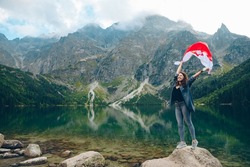 young pretty woman with poland flag in mountains near lake copy space