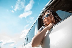 woman looking out from car window. road trip travel concept. summer sunny day