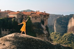 happy woman in yellow dress traveler meteora monastery on the background Greece