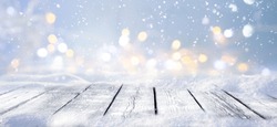 Winter snowy stage background with wooden flooring and Christmas lights on blue background, banner format, copy space.