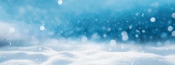Winter snow background with snowdrifts, with beautiful light and snow flakes on the blue sky, beautiful bokeh circles, banner format, copy space.