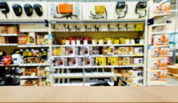 Mockup. Welding equipment. Shop with a variety of electrical equipment for welding. Defocused, blurred image. In the foreground is the top of a wooden table, counter.