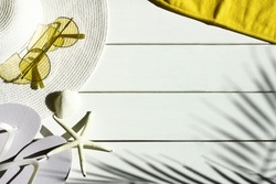 Summer vacation background of sunglasses, sun hat, shells, towel and  flip flops. Summertime, holiday, travel, beach, tourism concept. White and yellow colors.  Top view, space for text.