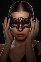close-up portrait of a beautiful girl with perfect make-up in a lace mask and hands near her face