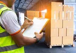 Worker Courier Holding Clipboard his Control Loading Package Boxes into Cargo Container.Supply Chain Commerce.Trucks Loading at Dock Warehouse. Inventory Management. Shipment.Shipping Truck Logistics