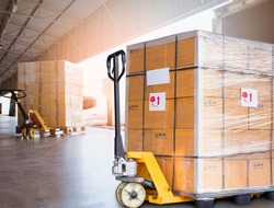 Large cargo shipment pallets. Hand pallet truck with stacked cardboard boxes wrapping plastic on pallet at warehouse dock. warehouse industry freight, logistics and transport. 