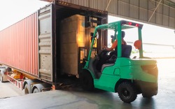 Forklift Tractor loading package boxes into shipping container at dock warehouse. Cargo shipment Loading truck. Supply Chain Freight truck. Industry warehouse logistics transportation.