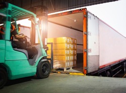 Forklift Tractor Loading Package Boxes into Cargo Container. TrailerTruck Parked Loading at Dock Warehouse. Shipment Delivery. Supply Chain. Shipping Warehouse Logistics Freight Truck Transportation.