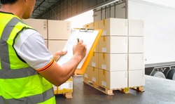 Worker Courier Holding Clipboard his Control Loading Package Boxes into Cargo Container.Supply Chain Commerce.Trucks Loading at Dock Warehouse. Inventory Management. Shipment.Shipping Truck Logistics	