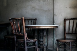 Vintage chairs and table as Chinese style with old wall in gray color in a room of house with dark tone of background. Concept of antique furniture, interior, home decorations, cafe, and restaurant.