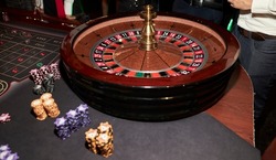 People play poker roulette at the table. Friends playing in the casino. A group of young people at a roulette table with a tape measure. Table for gambling in a luxury casino. Gambling Casino Roulette