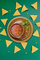 Bowl of delicious mexican chicken tortilla soup on green background with nachos chips. Photo as an illustration for a Mexican restaurant menu