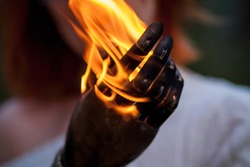 The girl's hand against the fire. Gesture of support. Burning hand. Bright symbol Flamy. Fire in the hand. A female hand of fire. Open female hands, in the flame. Revolution sign