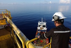 Worker watch Cargo being loaded from oil and gas platform onto a supply vessel