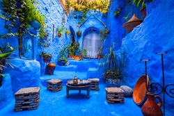Typical moroccan courtyard in Chefchaouen blue city medina in Morocco with blue walls and decorated with various objects (pots, jugs)
