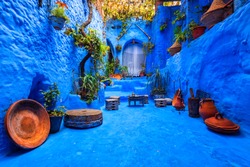 Fantastically beautiful moroccan courtyard in Chefchaouen blue city medina in Morocco with blue walls, architectural details, colorful flower pots and household items