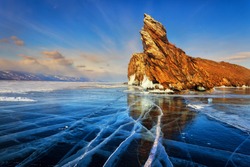 Lake Baikal in winter. Beautiful rocky island on a background of blue sky and smooth ice with cracks