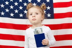Little beautiful girl with American dollars in the hands, Flag of America on background